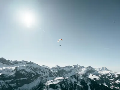 Paragliding over mountains under a clear sky